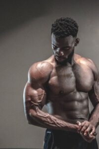 A strong, shirtless male bodybuilder showcasing muscles and strength in a gym setting.